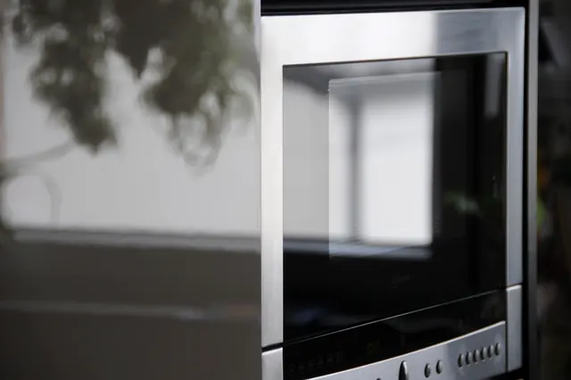Built-in stainless steel microwave with a dark glass door